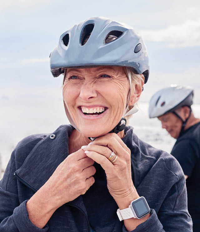Eine Frau lächelt, während sie im Freien Rad fährt und sich nach einer erholsamen Nacht voller Energie fühlt.