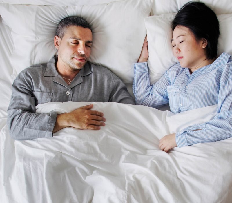 Ein im Bett liegendes Paar, von dem Einer an Schlafapnoe leidet