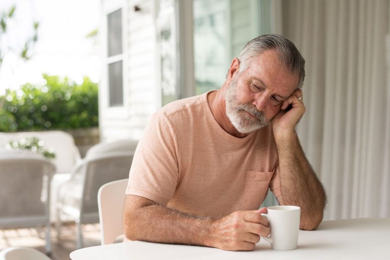 Man asleep at the breakfast bench with morning coffee due to untreated sleep apnea